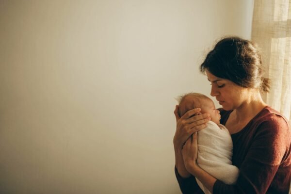 Mãe acolhendo o bebê recém-nascido junto à janela