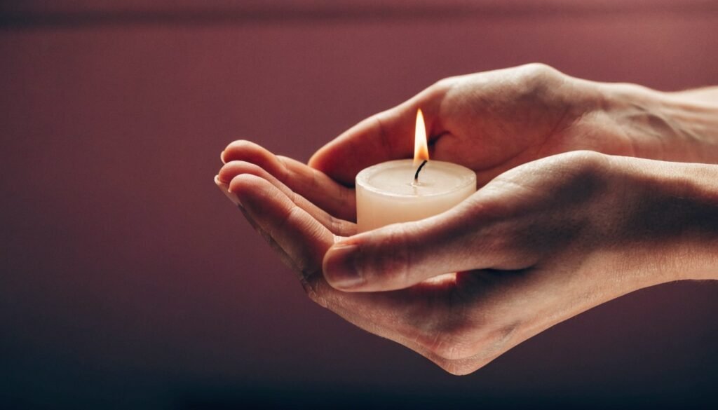 Mãos protegendo a chama suave de uma vela