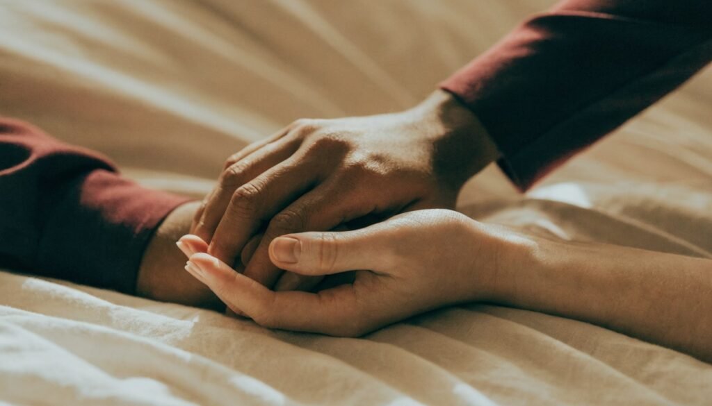 Mãos de um casal entrelaçadas com delicadeza