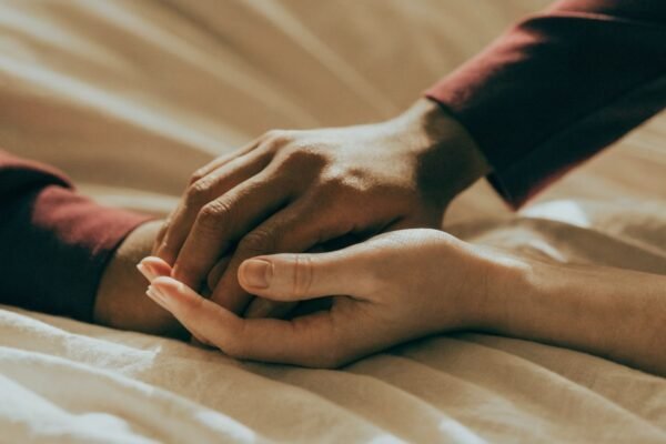 Mãos de um casal entrelaçadas com delicadeza